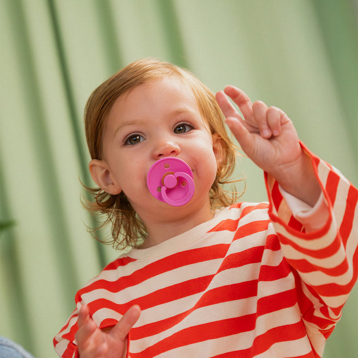 A toddler wearing BIBS bubblegum colour pacifier